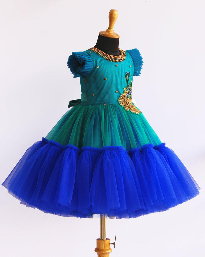 Peacock theme Applique Party wear Frock.
Material: Royal blue and Tourqise green colour net is using in the main portion of the dress. Royal blue colour net is pleating in the bottom portion. Over all colo