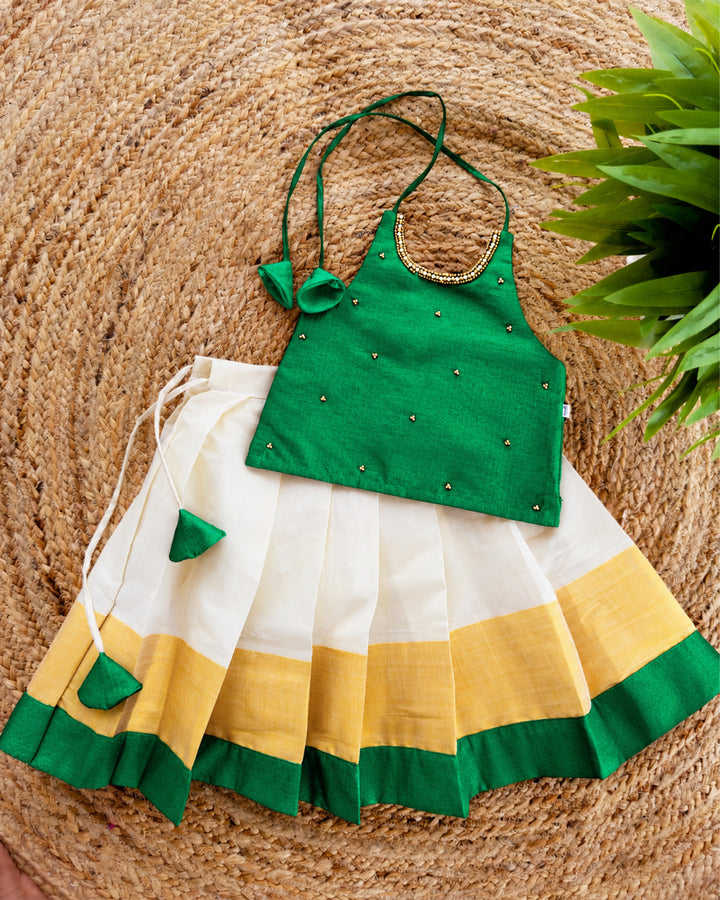 Cream green traditional Kerala Kasavu Onam lehenga choli for baby girl featuring an elegant ethnic design by Stanwells Kids.

