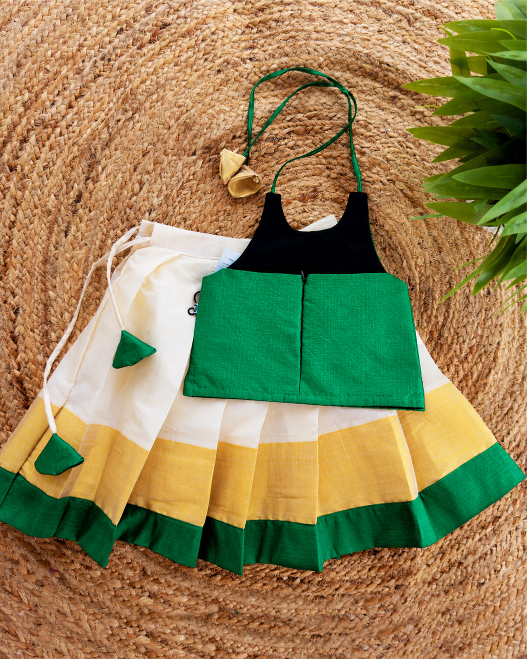 Back view of cream green Kerala Kasavu lehenga choli for baby girl highlighting the blouse design and traditional outfit details.