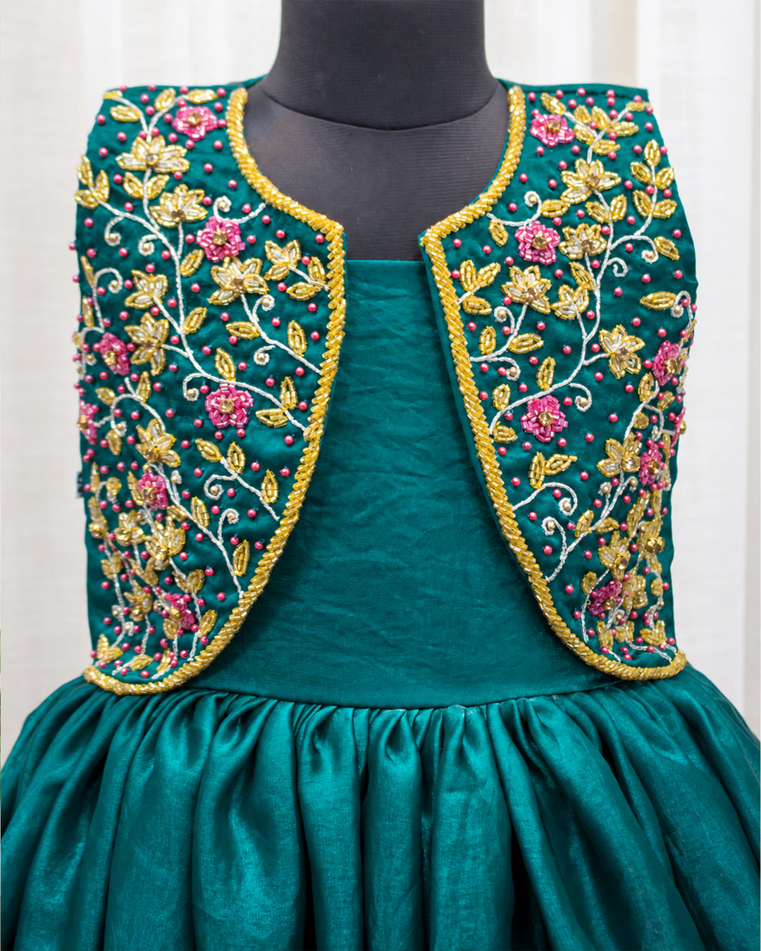 Detailed view of the beautifully designed peacock green ethnic jacket on a premium baby girl partywear gown.