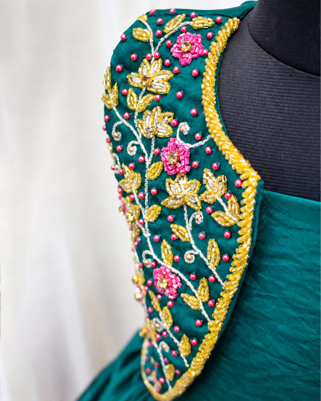 Close-up of intricate handwork detailing on the peacock green ethnic jacket gown for baby girl.