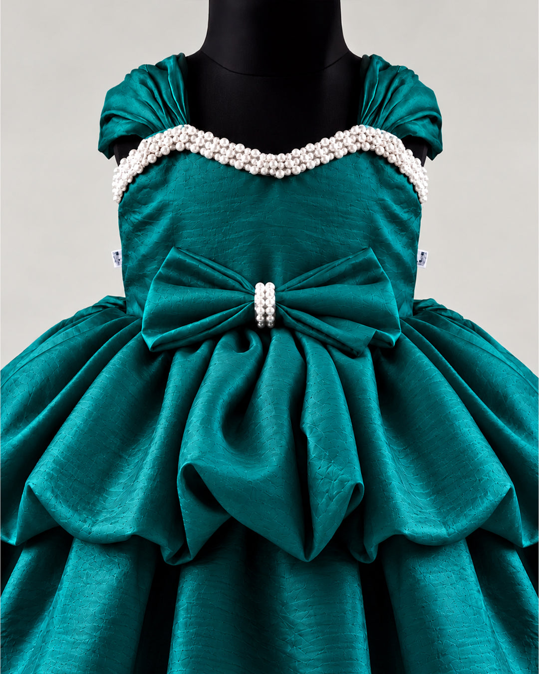 Detailed view of the peacock green silk skirt of a premium western-style party frock , Stanwells Kids.