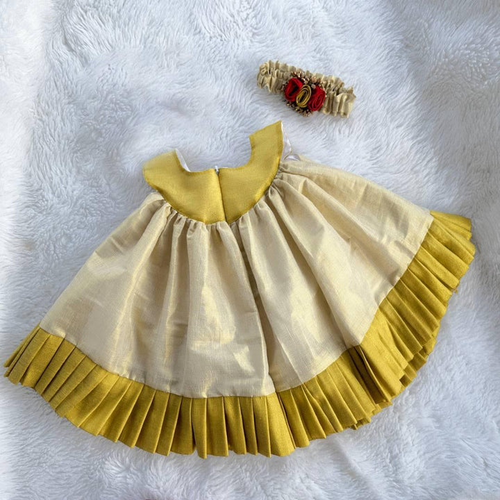 Cream & Gold Kerala Traditional Tissue frock - Matching Hairbad
Material: Cream shade kerala kasavu handloom fabric. Center portion is highlighted with red &amp; golden flowers with pollens attached. Beautifully designed outfit 