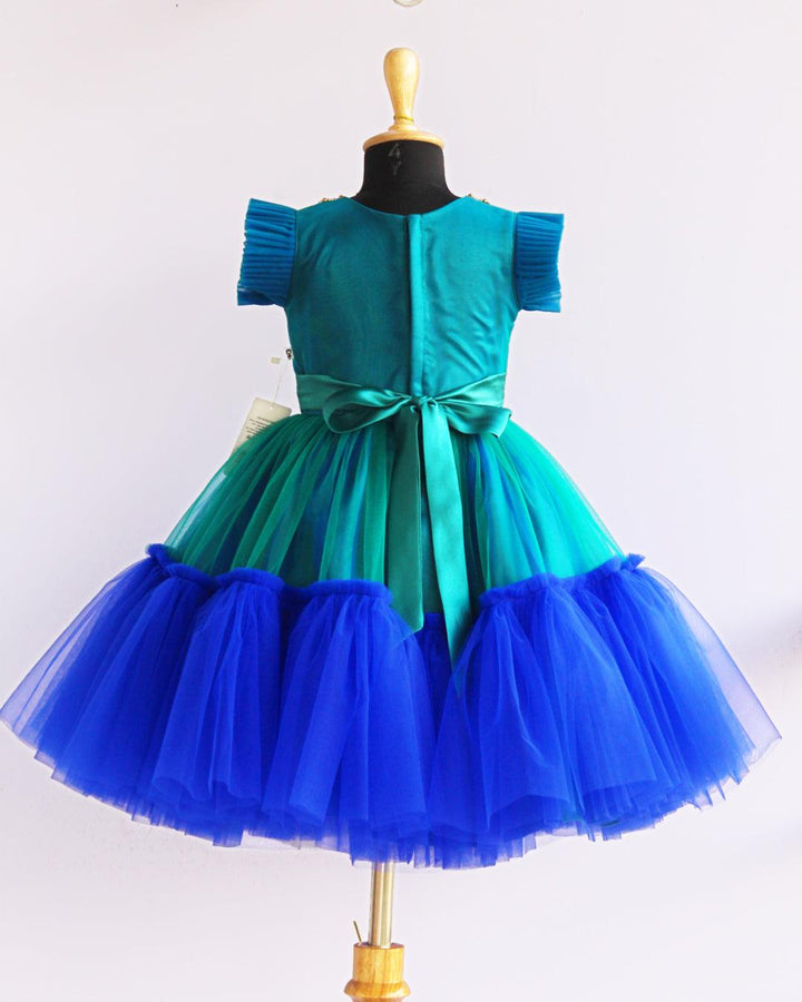 Peacock theme Applique Party wear Frock.
Material: Royal blue and Tourqise green colour net is using in the main portion of the dress. Royal blue colour net is pleating in the bottom portion. Over all colo