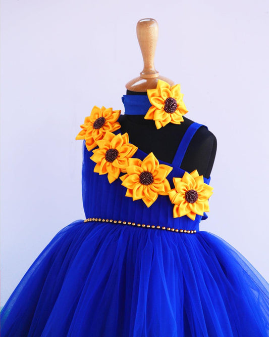 Sunflower theme royal blue and green colour  frock.
Material: Royal blue and green colour sunflower theme frock. Centre portion of the frock is hand beaded belt and the yoke portion yellow colour big satin sunflower 