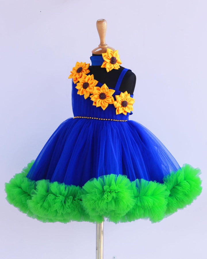 Sunflower theme royal blue and green colour  frock.
Material: Royal blue and green colour sunflower theme frock. Centre portion of the frock is hand beaded belt and the yoke portion yellow colour big satin sunflower 